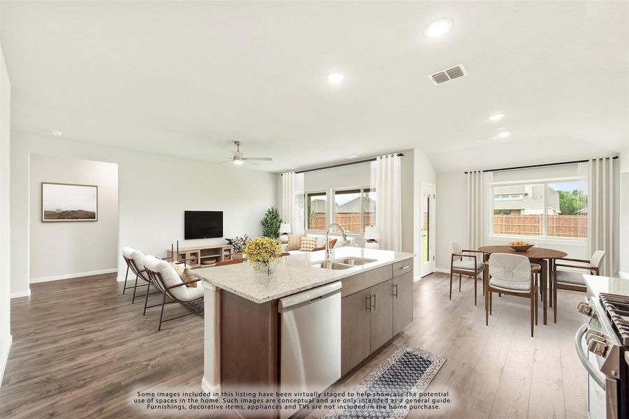 Open-concept kitchen with center island, granite countertops, and views into dining and living areas with hardwood floors