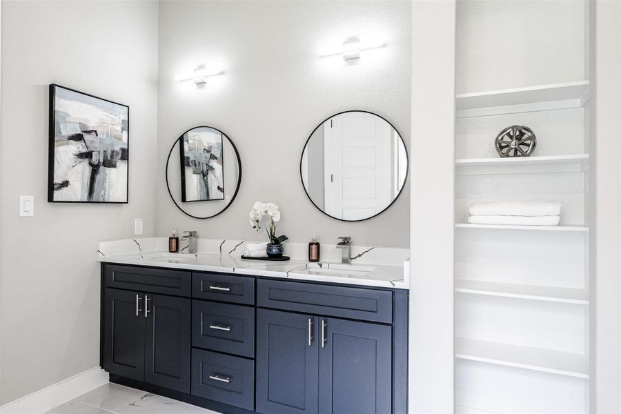 Double vanities with quartz countertops and sleek round mirrors elevate this bathroom's design. Double vanities with quartz countertops and sleek round mirrors elevate this bathroom's design.