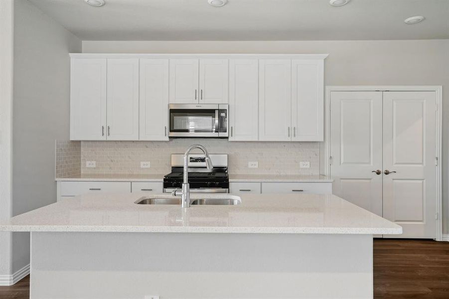 Kitchen with stainless steel appliances, light stone counters, and white cabinets