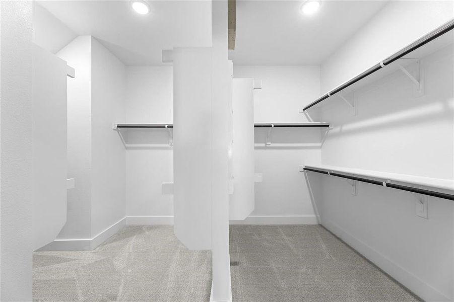 Walk-in closet featuring light gray carpeting, white walls, multiple shelving units, and recessed lighting Walk-in closet featuring light gray carpeting, white walls, multiple shelving units, and recessed lighting