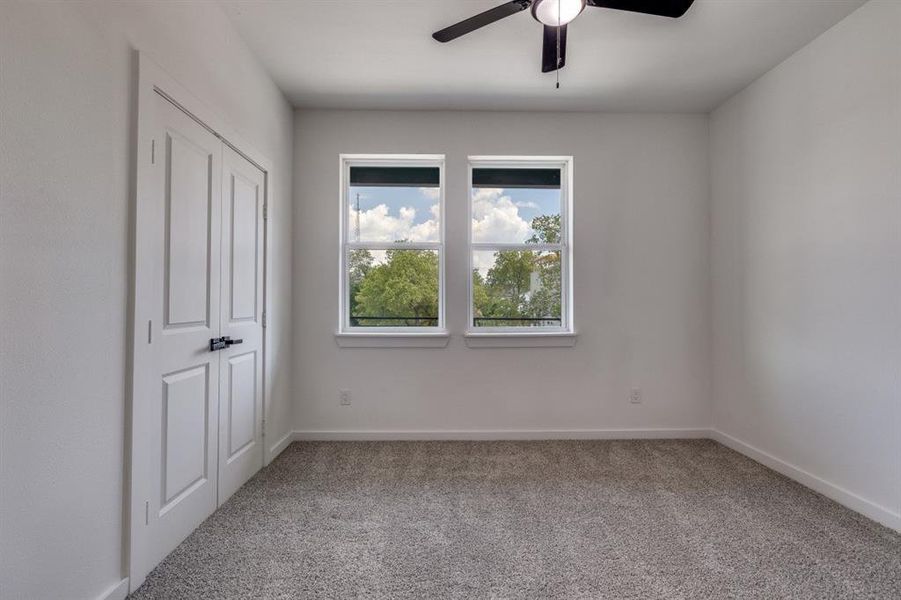 Unfurnished bedroom featuring light colored carpet and a ceiling fan Unfurnished bedroom featuring light colored carpet and a ceiling fan