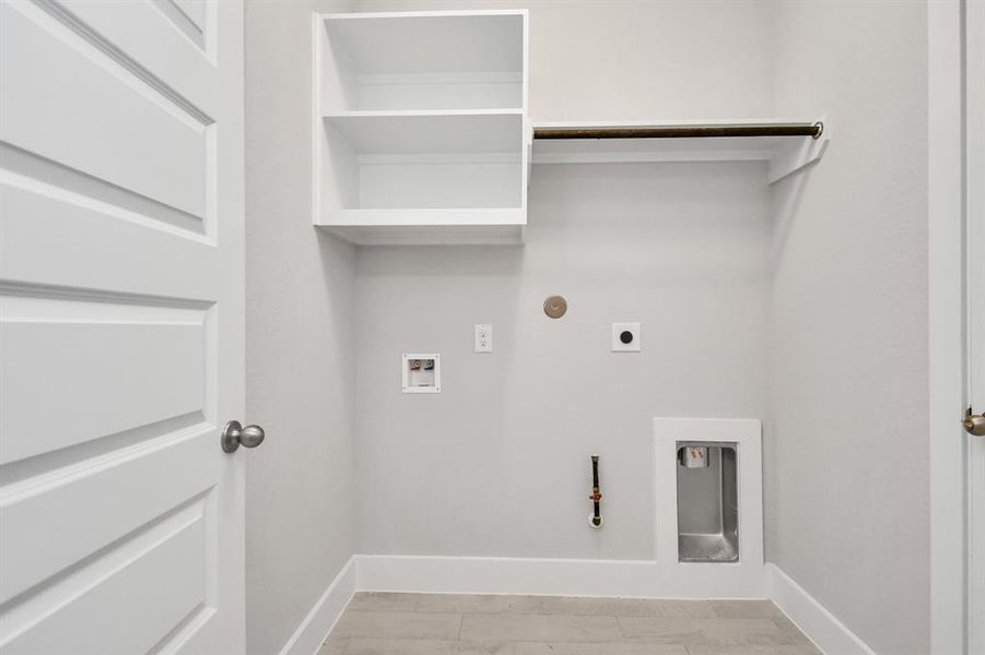 A perfect blend of functionality and comfort. Capture the essence of easy living with indoor laundry room, thoughtfully equipped with shelving for effortless organization. Both electric and gas connections available. Sample photo of completed home. Actual colors and selections will vary.