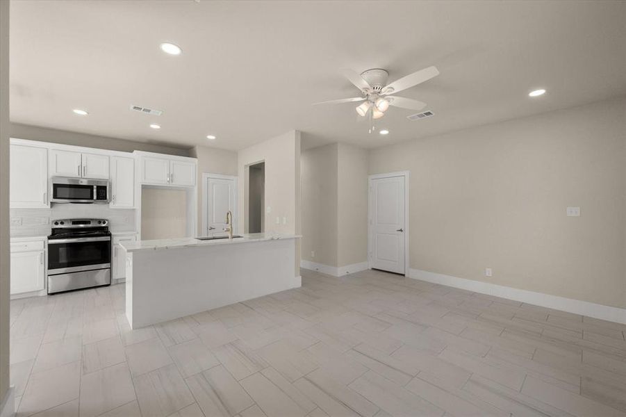 Kitchen with white cabinetry, ceiling fan, stainless steel appliances, decorative backsplash, and sink