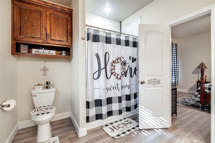 Bathroom with toilet, wood-type flooring, and a shower with shower curtain