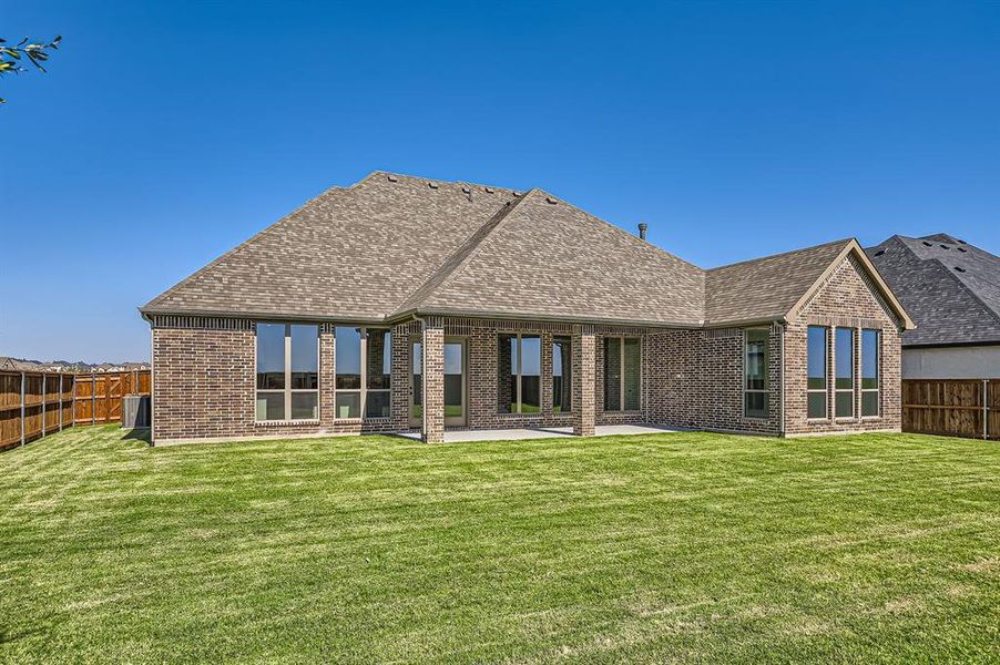 Rear view of property with a lawn and a patio area