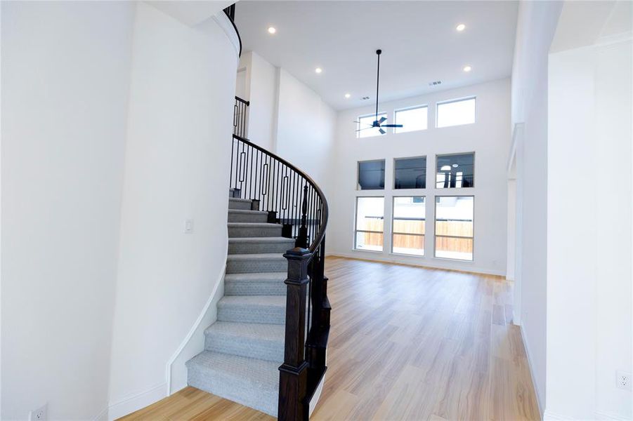 Stairway featuring wood finished floors, recessed lighting, and a towering ceiling Stairway featuring wood finished floors, recessed lighting, and a towering ceiling