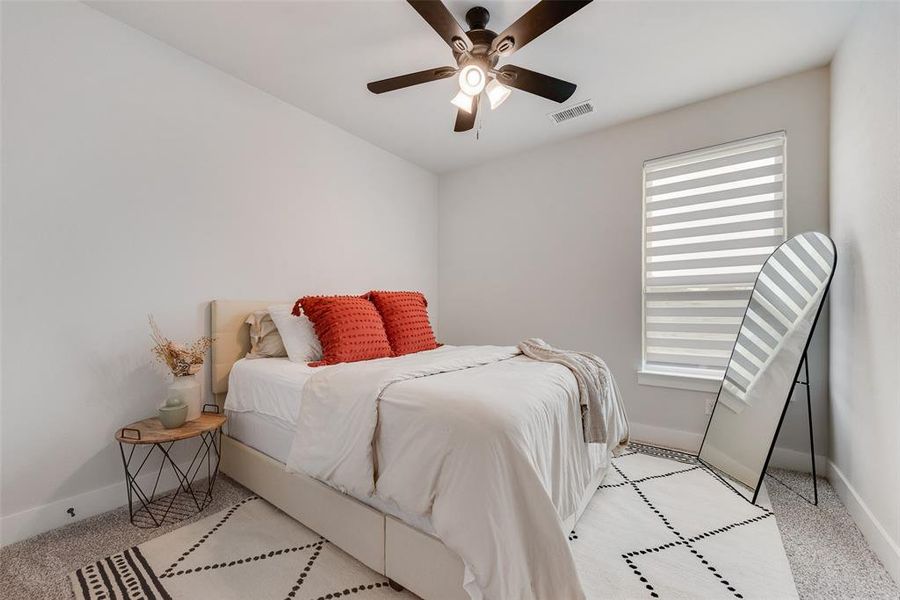 Carpeted bedroom featuring a ceiling fan with integrated lighting, a window with horizontal blinds, and neutral wall tones