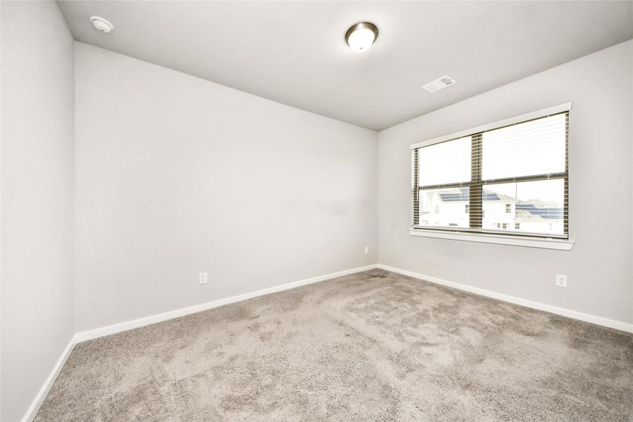 Spacious secondary bedroom with soft natural light, neutral finishes, and flexible use for guests, family, or a home office.
