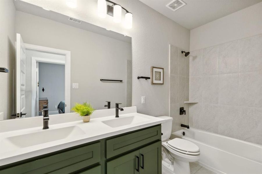 Full bathroom with tile patterned flooring, toilet, tiled shower / bath combo, and vanity