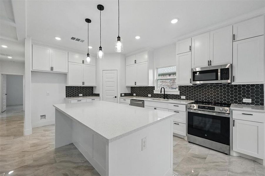 Kitchen with stainless steel appliances, light marble finish flooring, recessed lighting, a center island, and white cabinetry