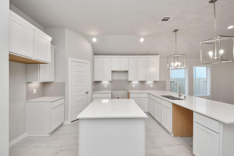 The kitchen is a culinary haven, featuring granite countertops, a tile backsplash, stainless steel appliances, 42” upper cabinets, and undercabinet lighting. Sample photo of completed home with similar floor plan. Actual colors and selections may vary.