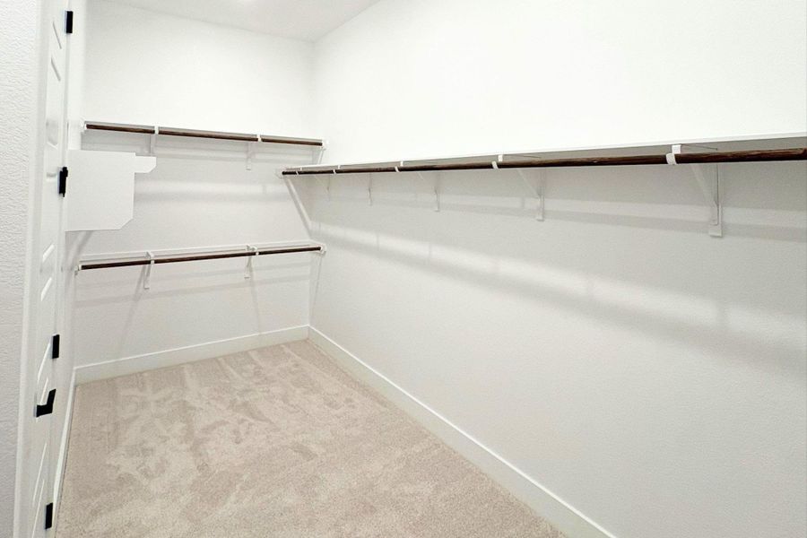 Ample built-in shelving and soft carpeting define this functional walk-in closet space. Ample built-in shelving and soft carpeting define this functional walk-in closet space.