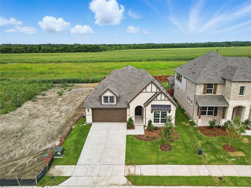 View of front facade featuring a view of countryside, driveway, a garage, a front lawn, and brick siding View of front facade featuring a view of countryside, driveway, a garage, a front lawn, and brick siding