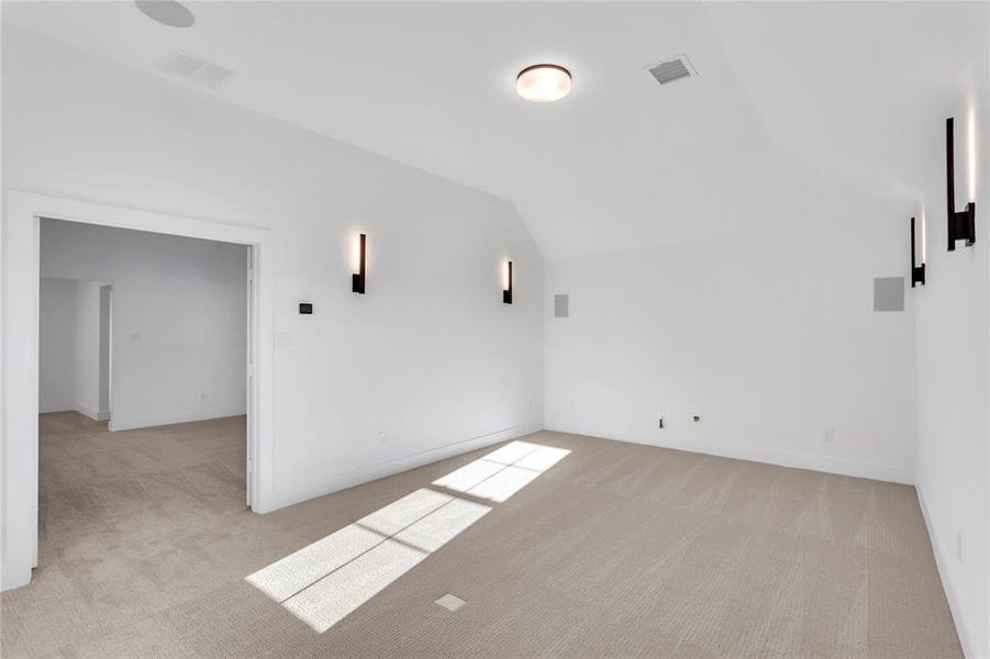 Additional living space with vaulted ceiling and light colored carpet