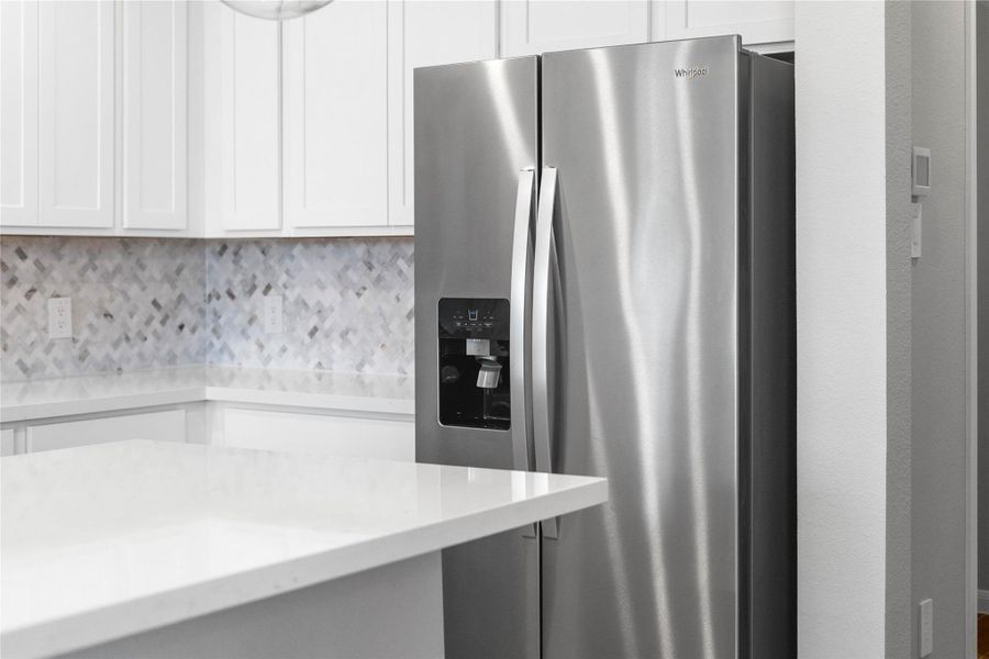 Kitchen comes equipped with a side-by-side Whirlpool refrigerator.