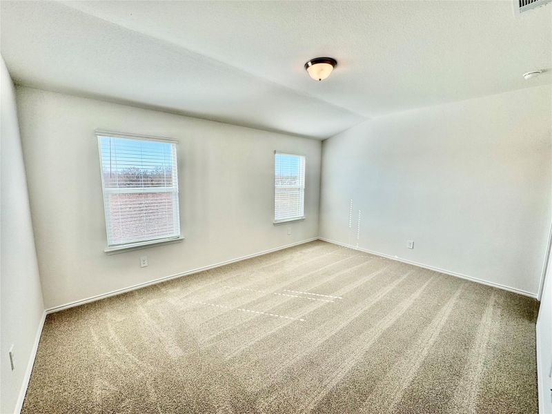 Carpeted empty room with a textured ceiling and vaulted ceiling