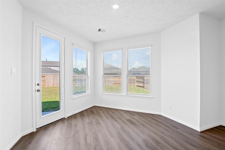 Start your day with a warm cup of coffee and quality time in this charming breakfast nook! Highlights include large windows with blinds, custom neutral paint, vinyl plank flooring, recessed lighting, high ceilings, and a convenient door leading to the rear patio slab and backyard.
