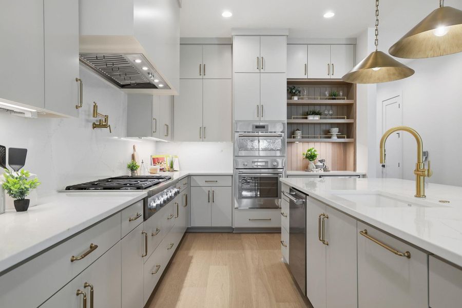 Kitchen with light wood-style flooring, open shelves, two tone cabinetry, stainless steel appliances, and decorative light fixtures
