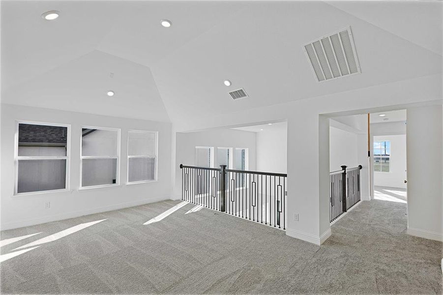 Corridor featuring light colored carpet and lofted ceiling