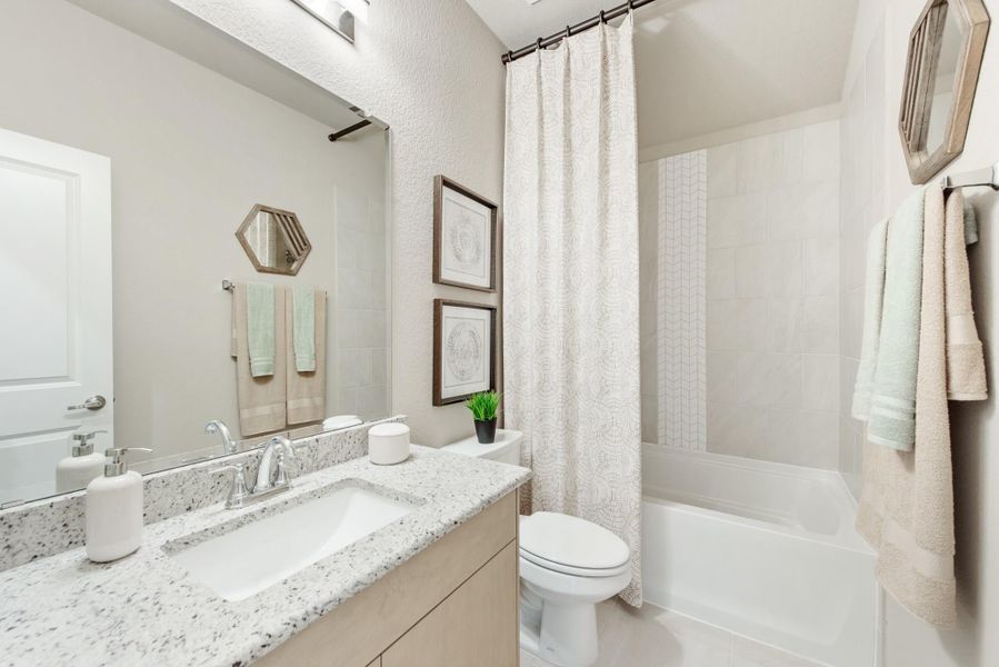 Bathroom with granite countertop vanity, white tub-shower combo, and light wood cabinets Bathroom with granite countertop vanity, white tub-shower combo, and light wood cabinets