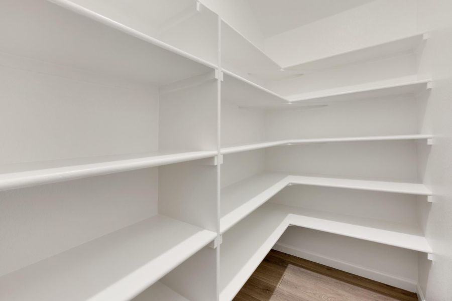 Walk-in pantry with white wrap-around shelving and hardwood floors, empty and ready for use Walk-in pantry with white wrap-around shelving and hardwood floors, empty and ready for use