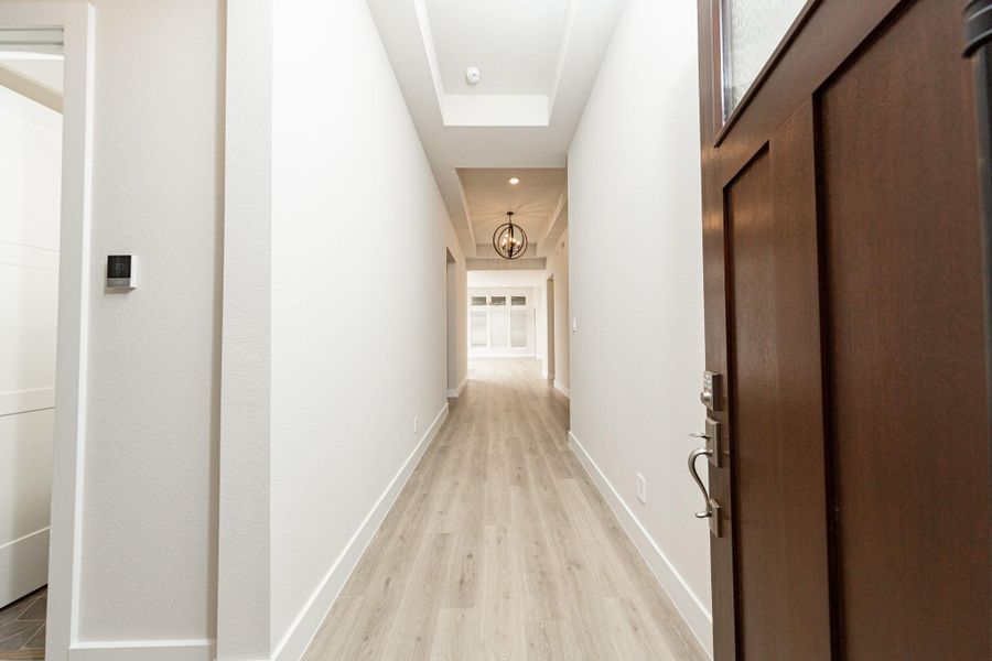 An inviting entrance opens up to an open-concept layout, seamlessly connecting the entry to the living areas with durable wood look tile flooring and striking architectural details. An inviting entrance opens up to an open-concept layout, seamlessly connecting the entry to the living areas with durable wood look tile flooring and striking architectural details.