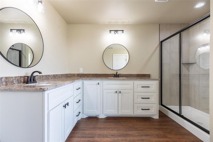 Bathroom featuring a dual vanity with white cabinetry, dark hardware, and stone-look countertops