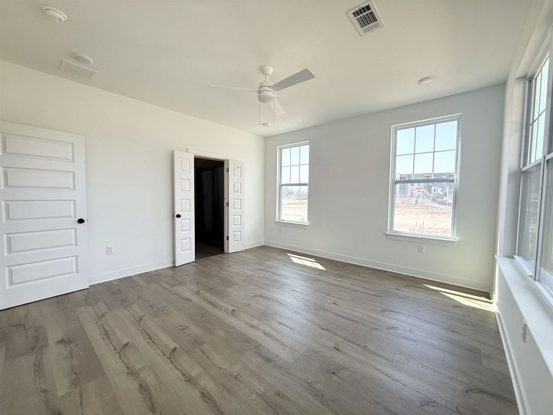 Unfurnished bedroom with ceiling fan and dark wood-style floors