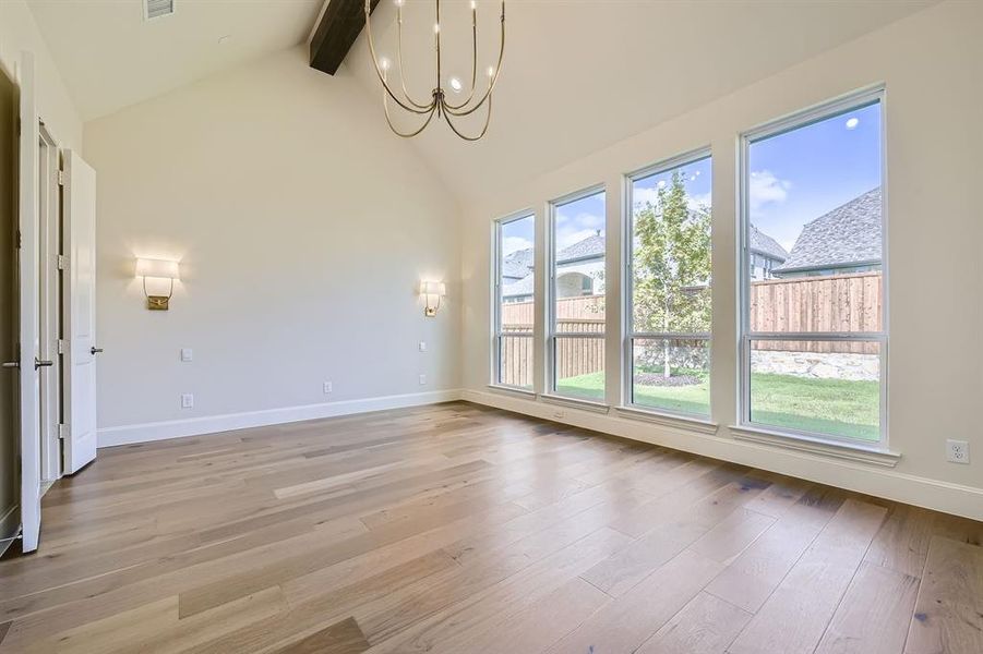 Primary bedroom with high vaulted ceiling, light hardwood / wood-style flooring, a notable chandelier, and beamed ceiling