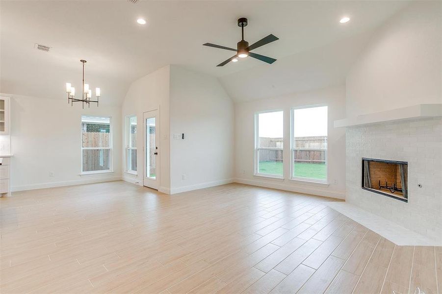 Unfurnished living room featuring light hardwood / wood-style flooring, lofted ceiling, and a wealth of natural light