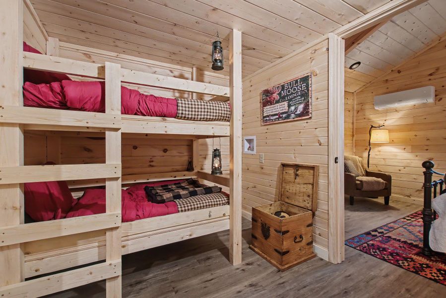 Bedroom featuring wood ceiling, wood walls, wood finished floors, a wall mounted air conditioner, and vaulted ceiling