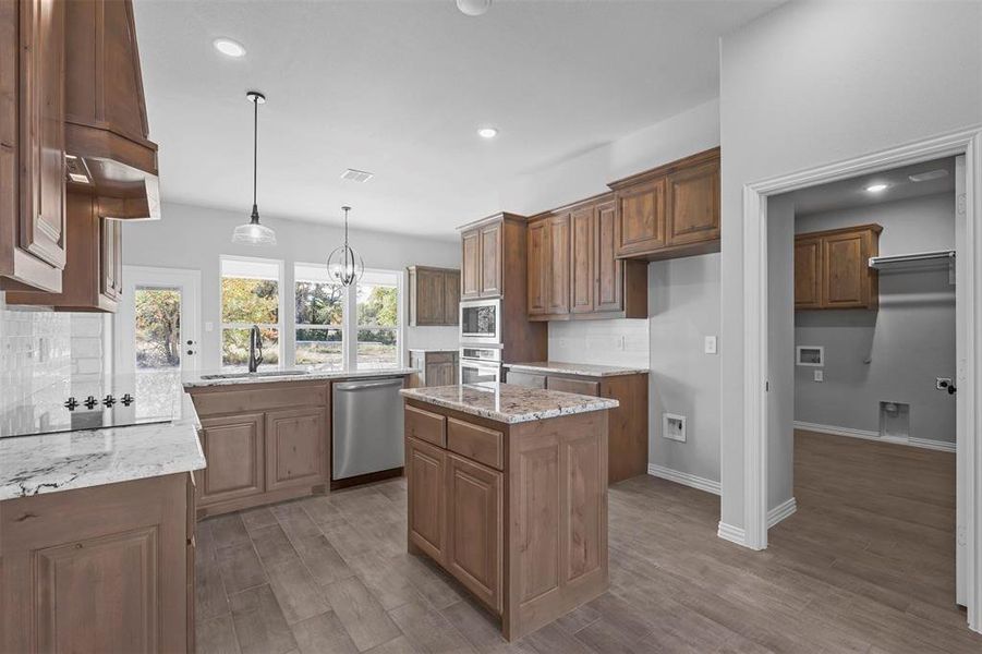 Kitchen with a center island, appliances with stainless steel finishes, sink, dark hardwood / wood-style floors, and pendant lighting