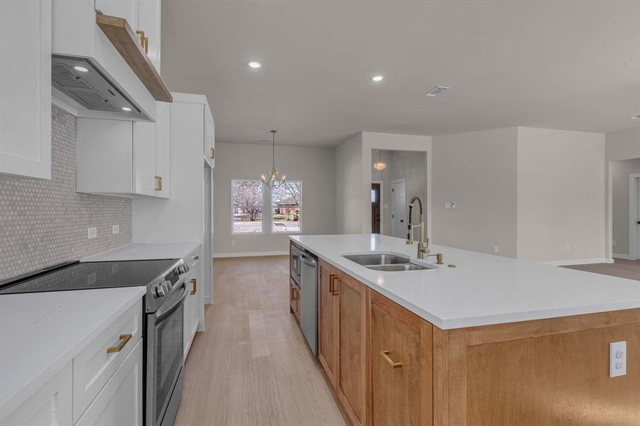 Kitchen with an island with sink, appliances with stainless steel finishes, sink, and white cabinets