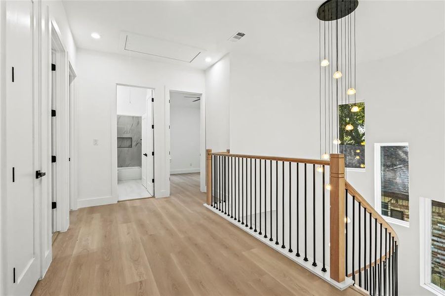 Corridor with wood finished floors, recessed lighting, an upstairs landing, and attic access