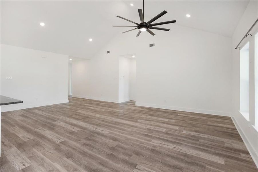 Unfurnished living room featuring light wood finished floors, high vaulted ceiling, recessed lighting, and ceiling fan.