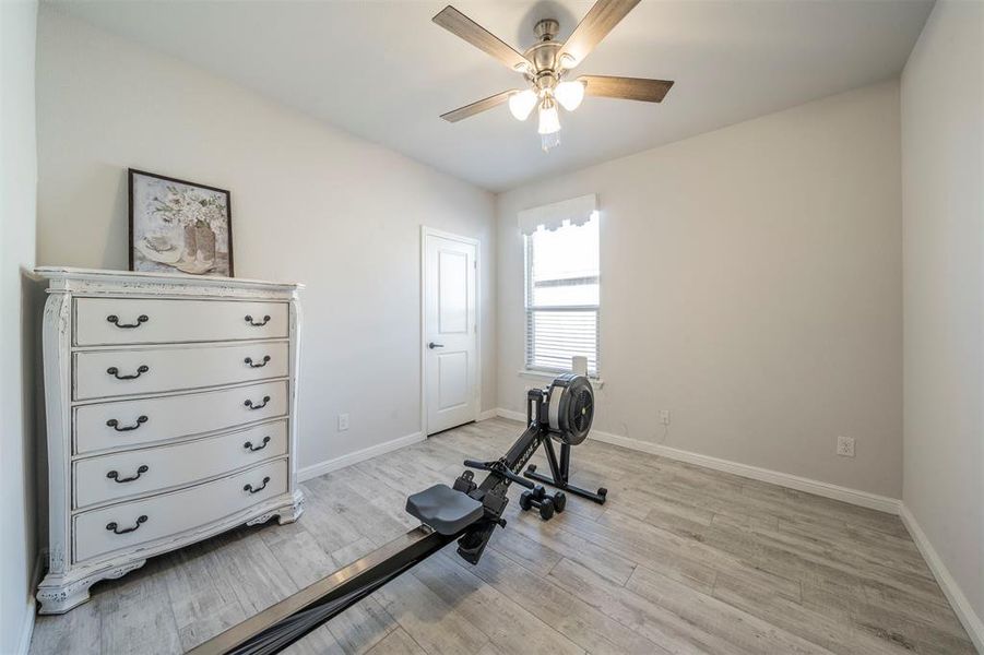 Workout area with ceiling fan and light wood-type flooring