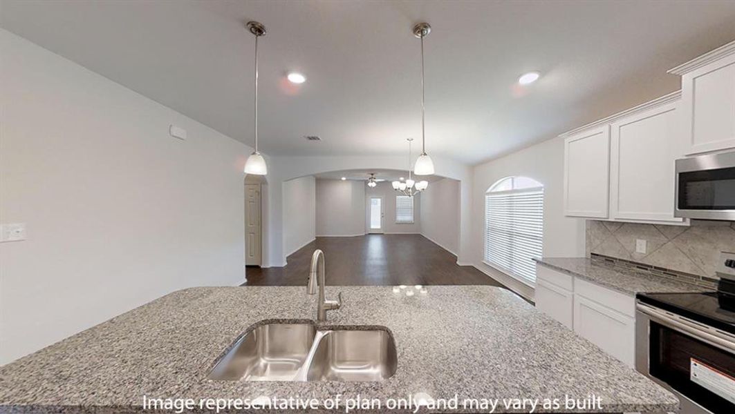 Kitchen featuring stainless steel appliances, white cabinetry, dark wood-type flooring, hanging light fixtures, and tasteful backsplash Kitchen featuring stainless steel appliances, white cabinetry, dark wood-type flooring, hanging light fixtures, and tasteful backsplash