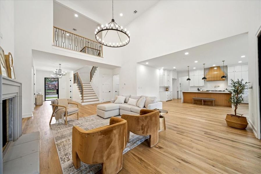 Living room featuring a high ceiling, hardwood flooring, and a notable chandelier