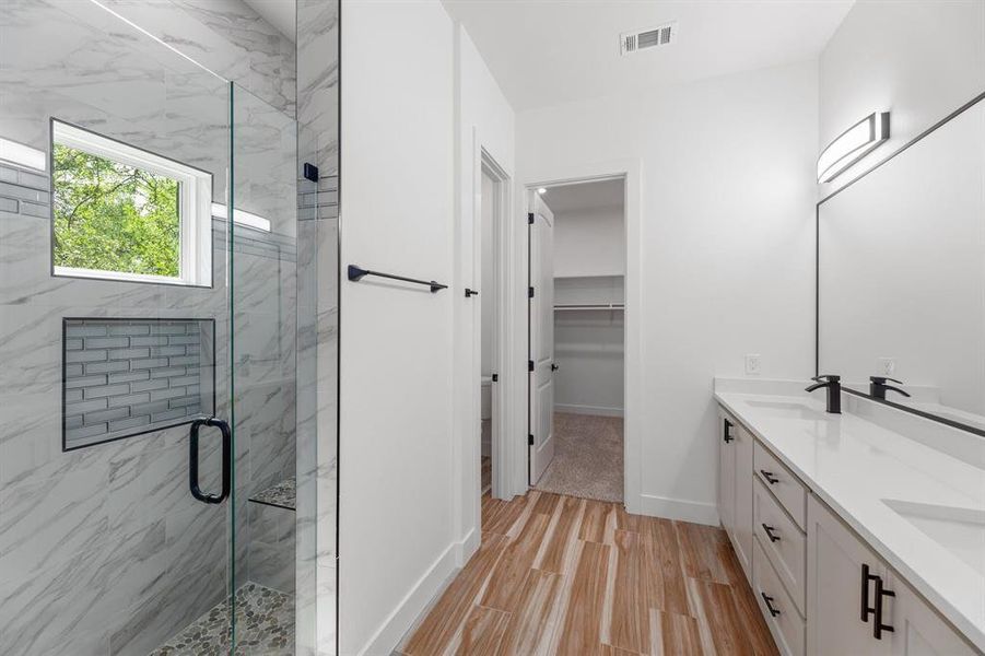 Full bathroom featuring a marble finish shower, wood finished floors, and a double vanity