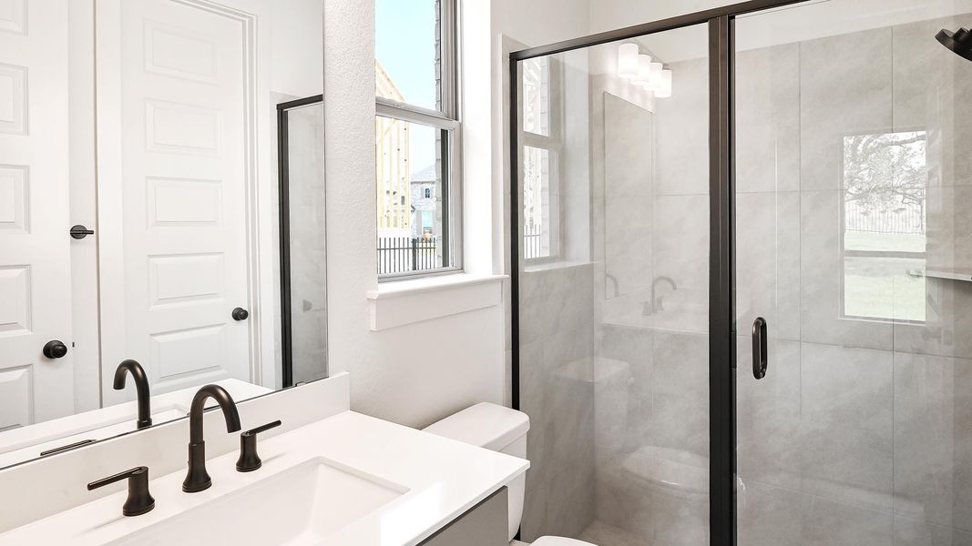 Bathroom with vanity, toilet, a stall shower, and plenty of natural light