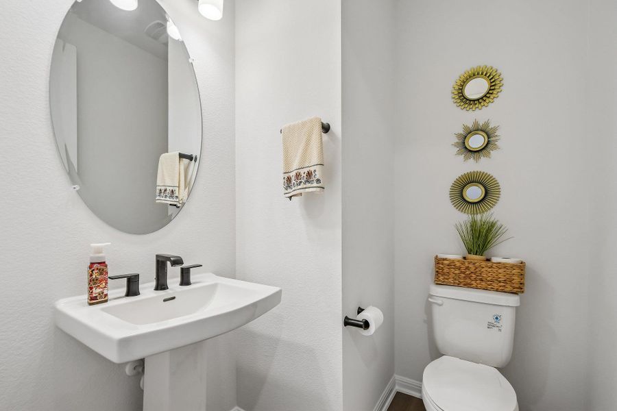 A compact and functional powder room with a modern pedestal sink and elegant wall decor.