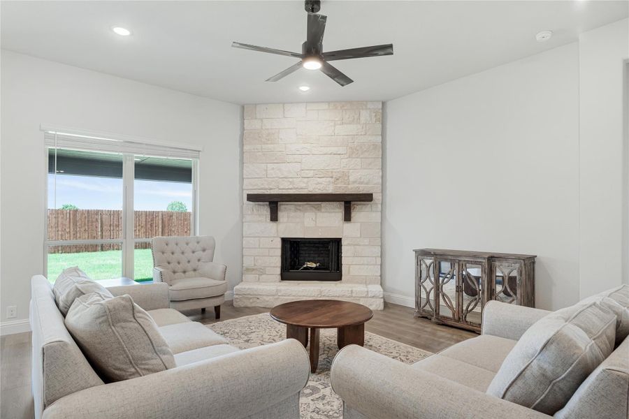 Living room with floor-to-ceiling stone fireplace, gray sofas, ceiling fan, and hardwood floors
