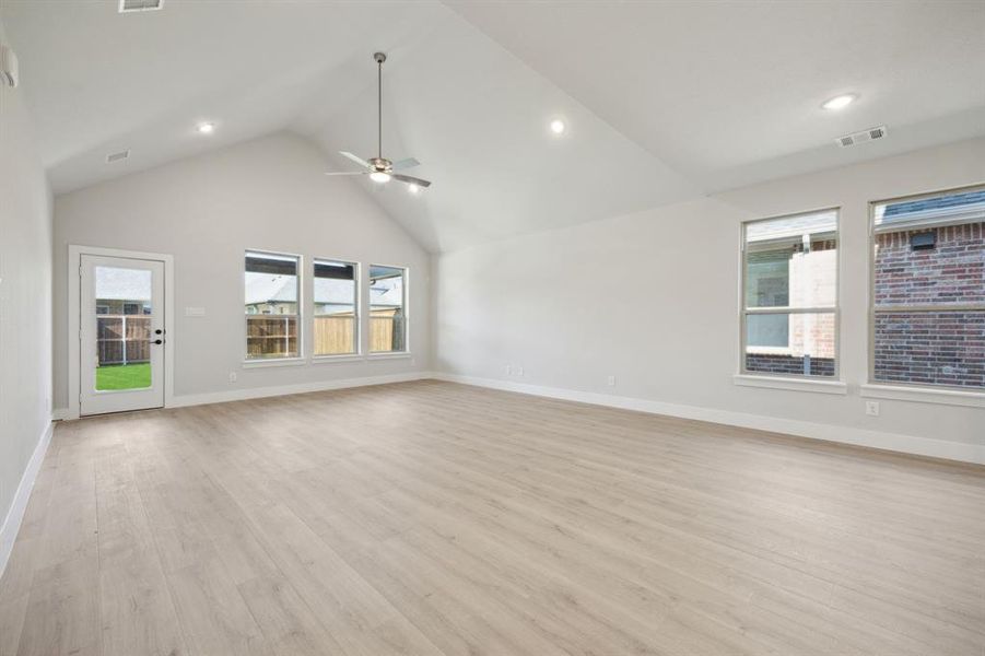 Unfurnished living room featuring high vaulted ceiling, ceiling fan, a wealth of natural light, and light hardwood / wood-style flooring