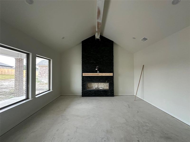 Unfurnished living room featuring a fireplace and unfinished concrete flooring