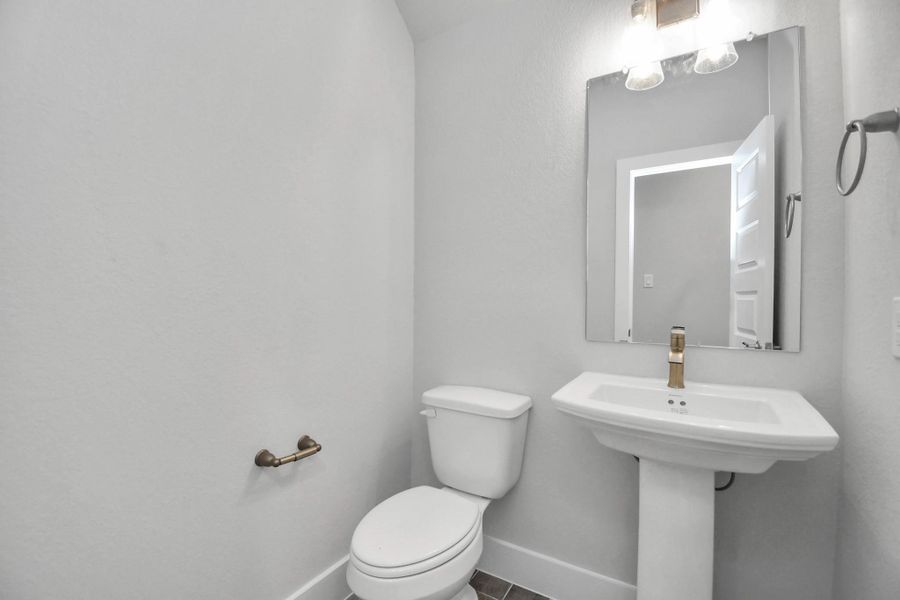 This half bathroom features a stylish pedestal sink, modern hardware, and bright recessed lighting, creating a sleek and inviting space.