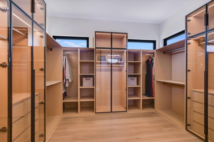 Walk in custom closet featuring light wood-type flooring, lots of customized storage for your wardrobe Walk in custom closet featuring light wood-type flooring, lots of customized storage for your wardrobe