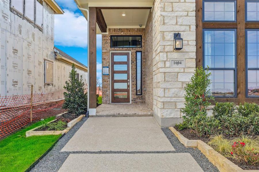 Stone and brick exterior featuring a covered entry, wood-paneled windows, and a modern front door with frosted glass panels