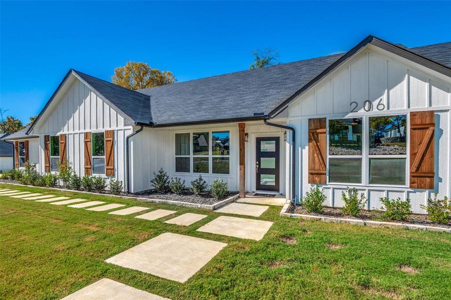 Modern farmhouse style home with a front yard, board and batten siding, and a shingled roof