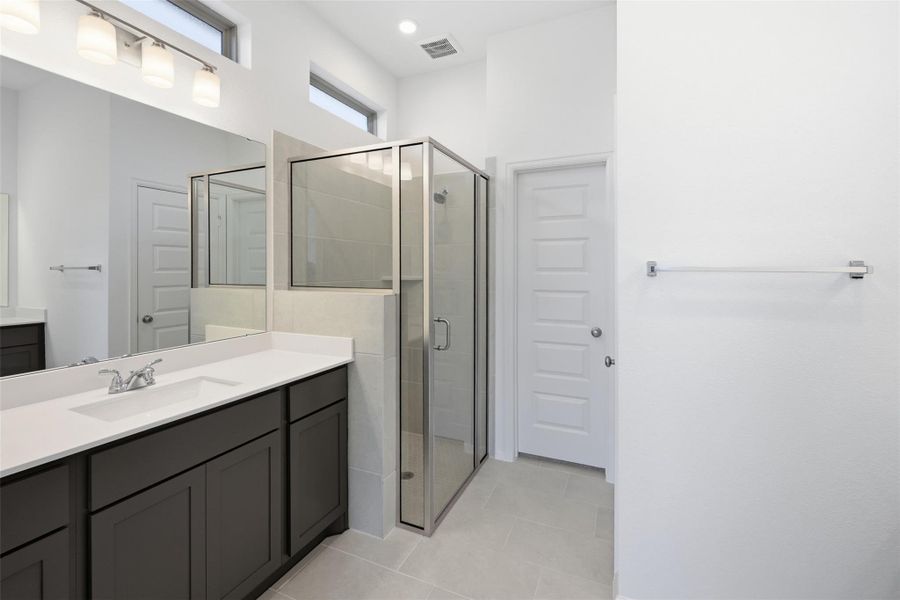 Modern bathroom featuring a spacious glass enclosed shower, sleek double vanity with ample storage, and contemporary fixtures, all accented by bright natural light.