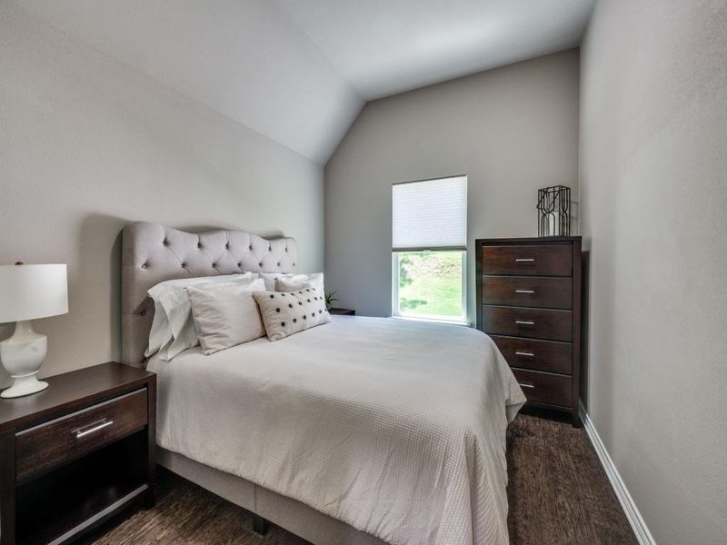 Bedroom with dark wood-type flooring, lofted ceiling, and baseboards Bedroom with dark wood-type flooring, lofted ceiling, and baseboards